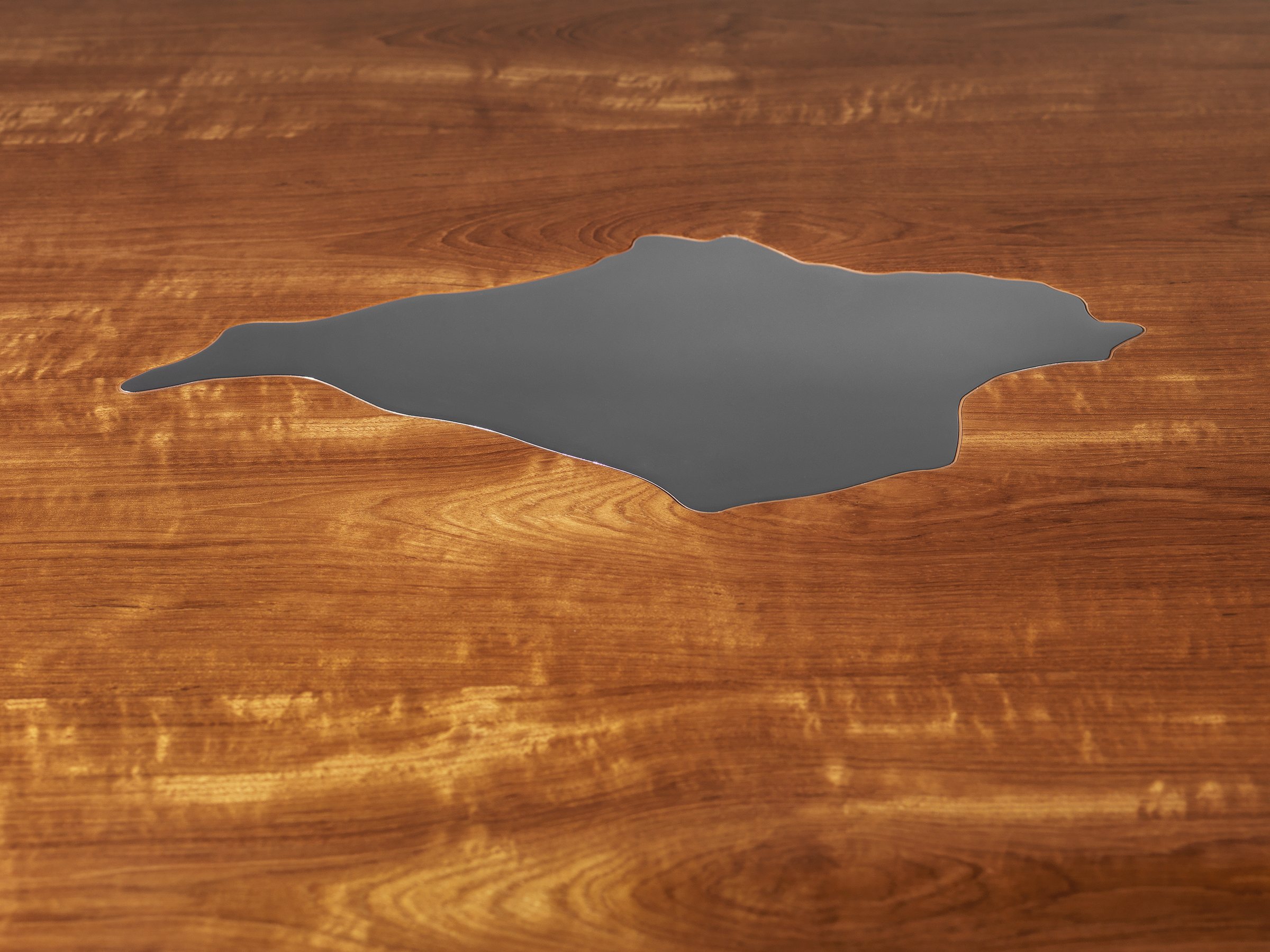 Close-up detail of the laser-cut stainless-steel Isle of Wight inlay set into the teak